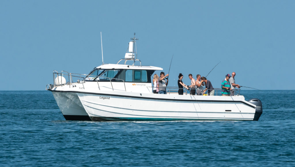Epic Fishing 5 A white Legend boat from Epic Fishing Trips carries anglers on calm seas near New Quay, Wales, with Cardigan Bay stretching behind.